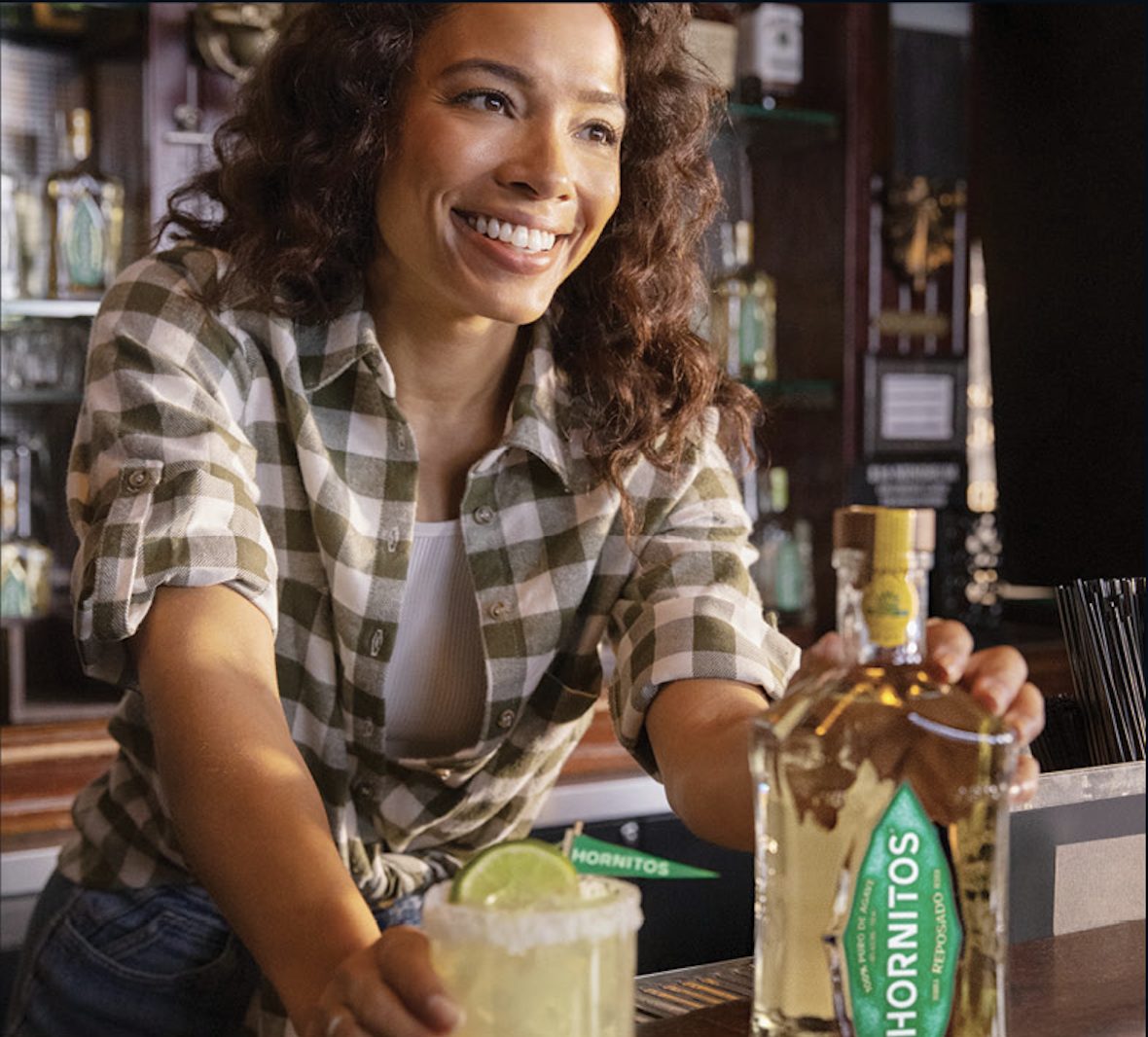 A smiling bartender sliding a Hornitos Margarita across the bar.